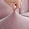 A hand is adjusting the fabric of a pink stretchable chenille sofa cushion cover.