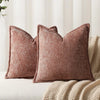 A close-up of a textured, dusty rose chenille throw pillow resting on a beige knitted blanket.