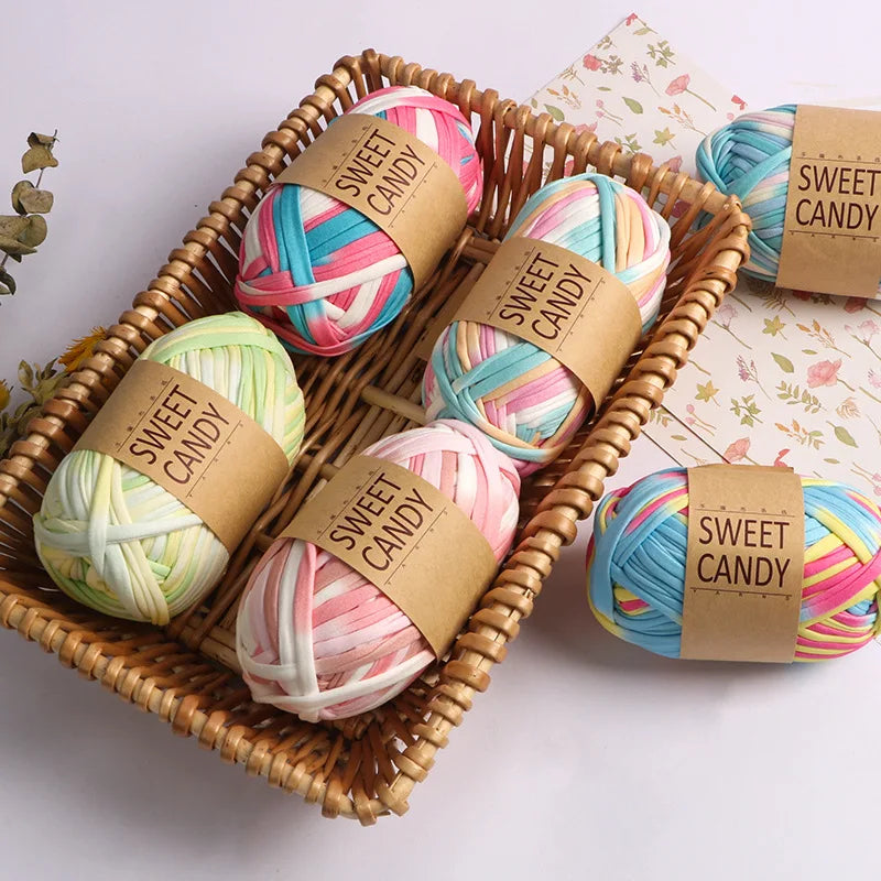 A woven basket filled with pink, blue, and white hand-dyed fabric strip yarn balls labeled Sweet Candy.