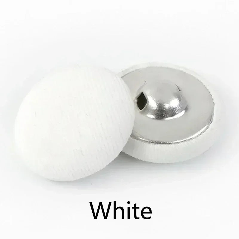 A white round fabric-covered shank button is shown next to its silver metal base.