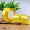 A roll of yellow satin ribbon for gift wrapping and DIY crafts resting on a wooden surface.