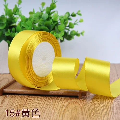 A roll of yellow satin ribbon for gift wrapping and DIY crafts resting on a wooden surface.