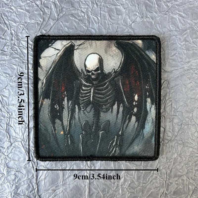 A black embroidered patch featuring a stylized skull with dark wings on a gray background.
