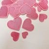 A collection of 24 pink iron-on love heart embroidered patches for DIY clothing.
