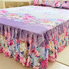 A purple and pink floral print bed skirt set with a matching duvet cover on a bed.