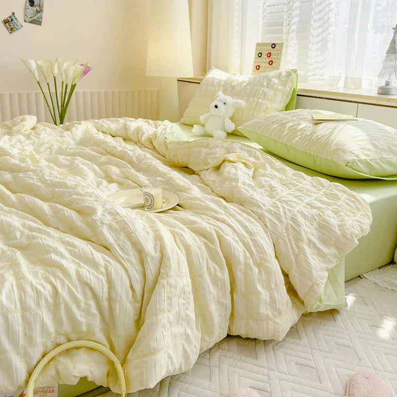 A light yellow summer seersucker quilt comforter spread on a bed with white bedding and a small white stuffed animal.