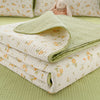 A stack of light green and cream quilted blankets with floral patterns resting on a lime green surface.