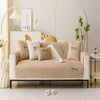 A beige plush sofa cover with decorative pillows and a light wood accent in a bright, modern living room.