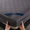 A hand is holding a gray quilted mattress protector with the Healthy Sleep branding.