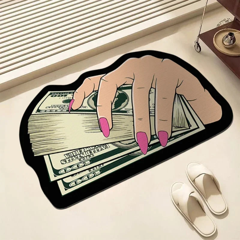 A hand is holding a stack of US dollar bills on a black decorative floor rug.