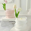 A stack of sheer pink and white organza ribbon rolls for gift wrapping and crafts displayed on a white surface.