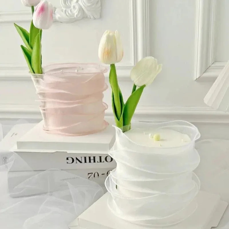 A stack of sheer pink and white organza ribbon rolls for gift wrapping and crafts displayed on a white surface.