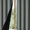 A close-up view of dark gray blackout curtains hanging next to a glass door.
