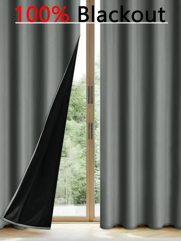 A close-up view of dark gray blackout curtains hanging next to a glass door.