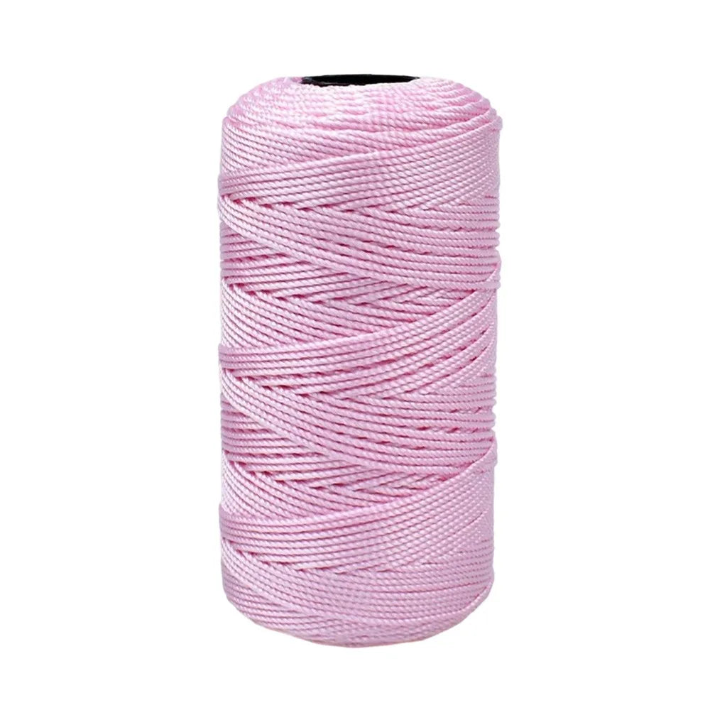 A spool of pink cotton silk thread for knitting and crafting.
