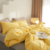 A bright yellow duvet cover set with pom-pom decoration is displayed on a bed.