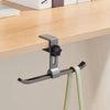 A silver adjustable aluminum desk hook with dual clips is shown hanging from a wooden shelf.