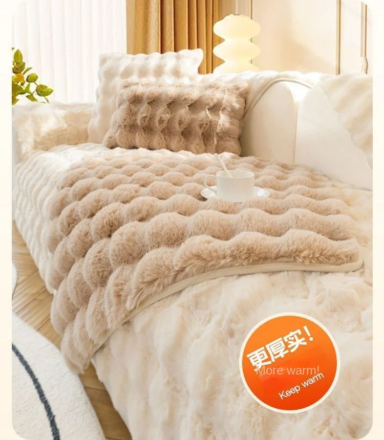 A fluffy beige rabbit fur sofa cushion cover displayed on a white bed with light curtains.