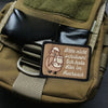 A close-up of a tactical green pouch featuring an embroidered patch with text in German.