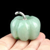 A smooth, pale green natural stone pumpkin figurine with a silver stem is held in a hand.