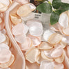 A close-up of pink and cream silk rose petals arranged on a satin fabric for weddings and events.