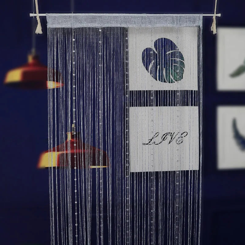 A vertical string curtain made of blue beads with a heart design and the word LOVE displayed on a white rectangle.