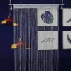 A vertical string curtain made of blue beads with a heart design and the word LOVE displayed on a white tag.