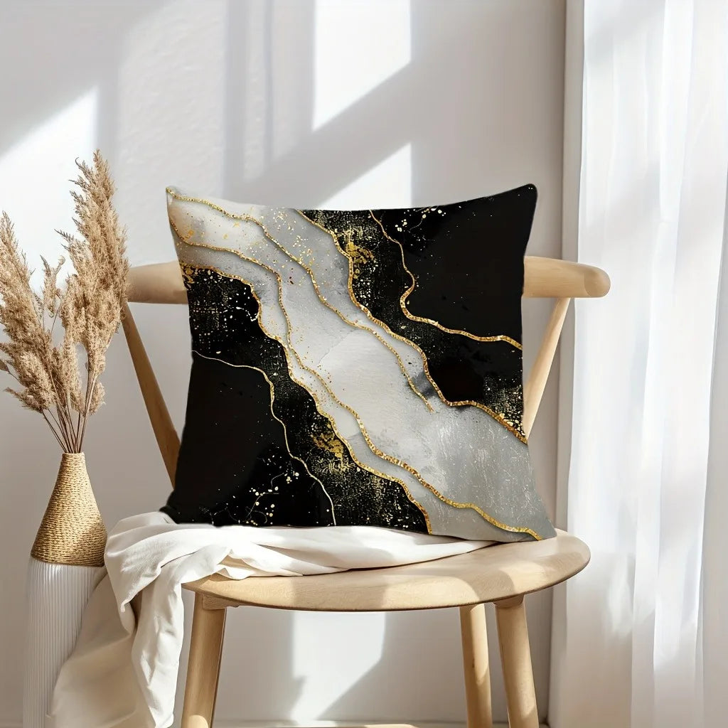 A black decorative pillow with gold marble print texture resting on a wooden chair.