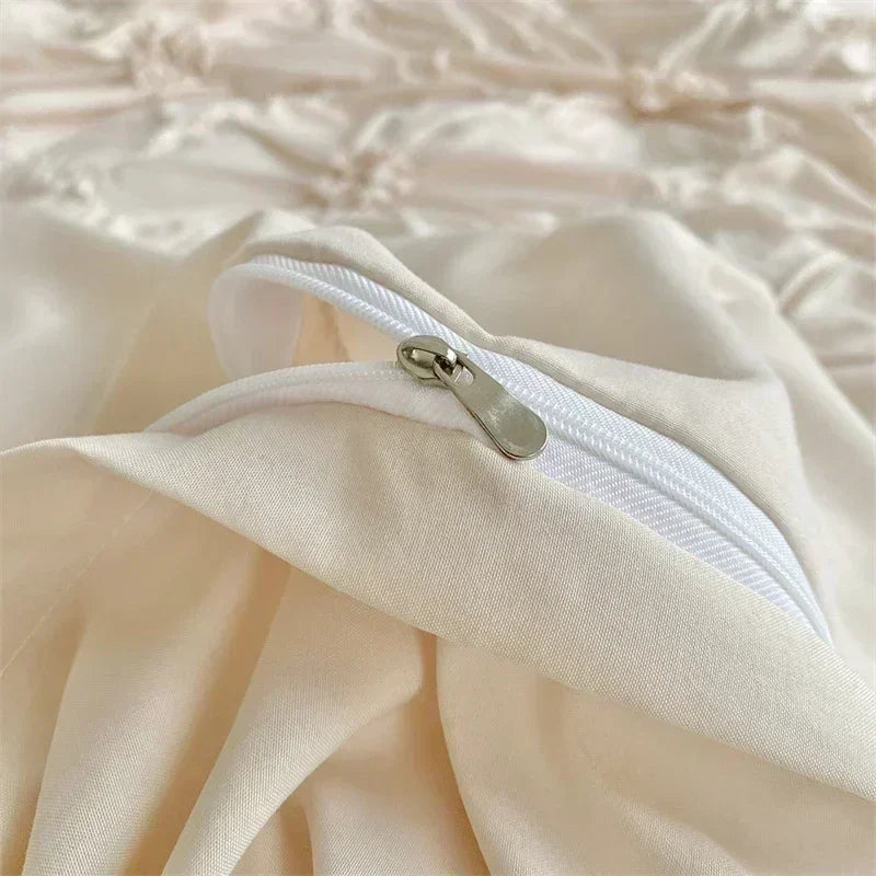 A close-up of a light beige pinch pleat duvet cover set for king size bedding showing a white zipper detail.