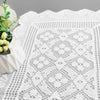 White lace table runner with a decorative pattern and a small white flower arrangement.