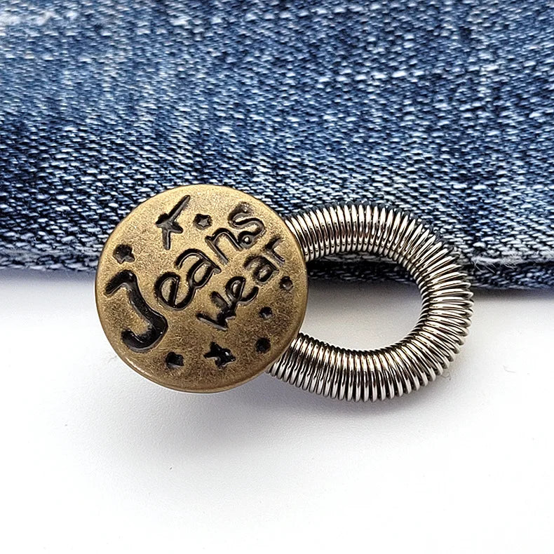 A round brass button with the text Jeans wear engraved on it, resting on a denim fabric background.
