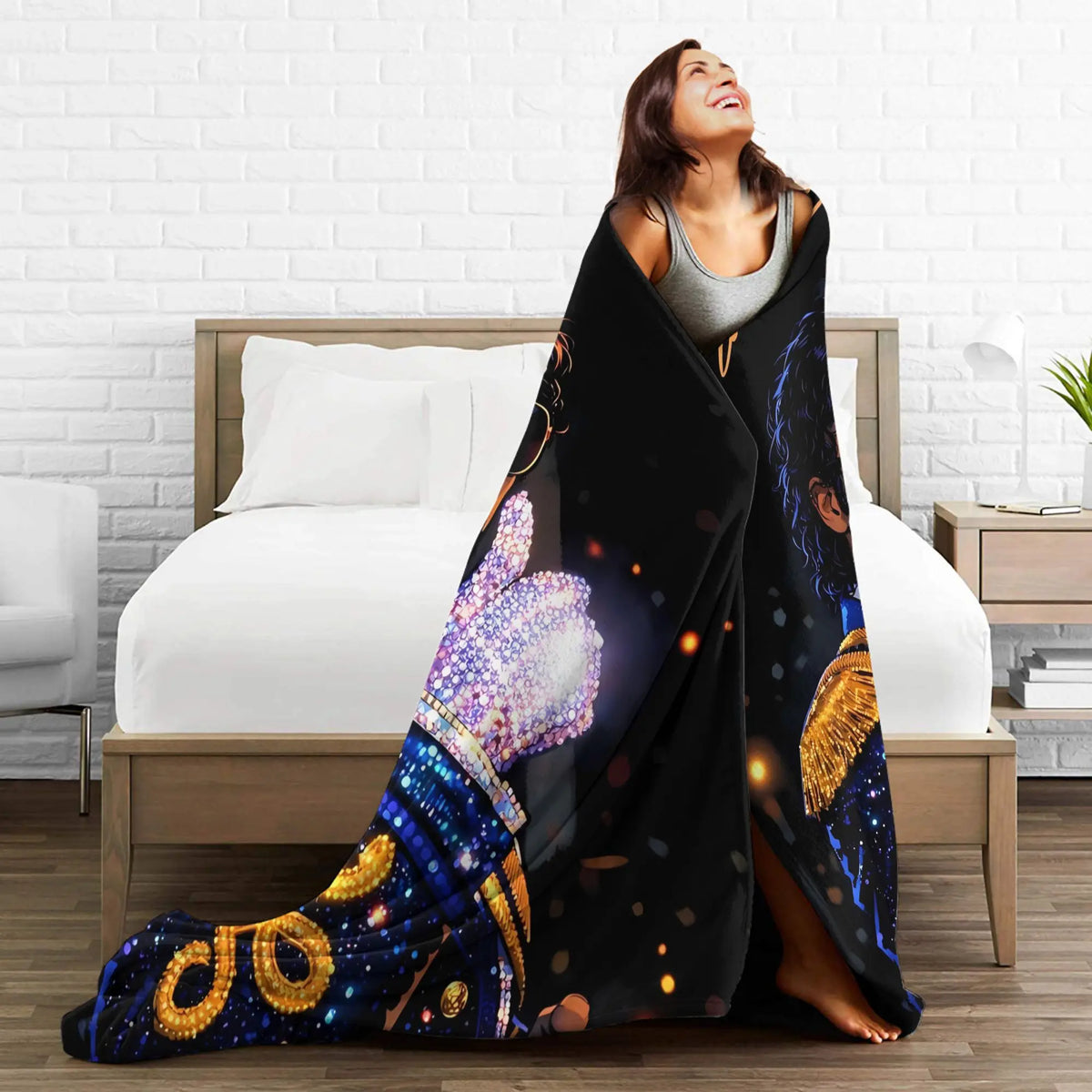 A woman is relaxing on a bed with a black and blue graphic throw blanket draped over her.