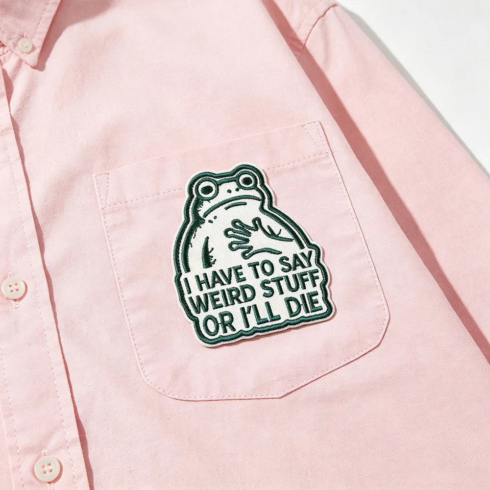 Pink shirt with an embroidered frog patch on the chest that says I have to say weird stuff or I'll die