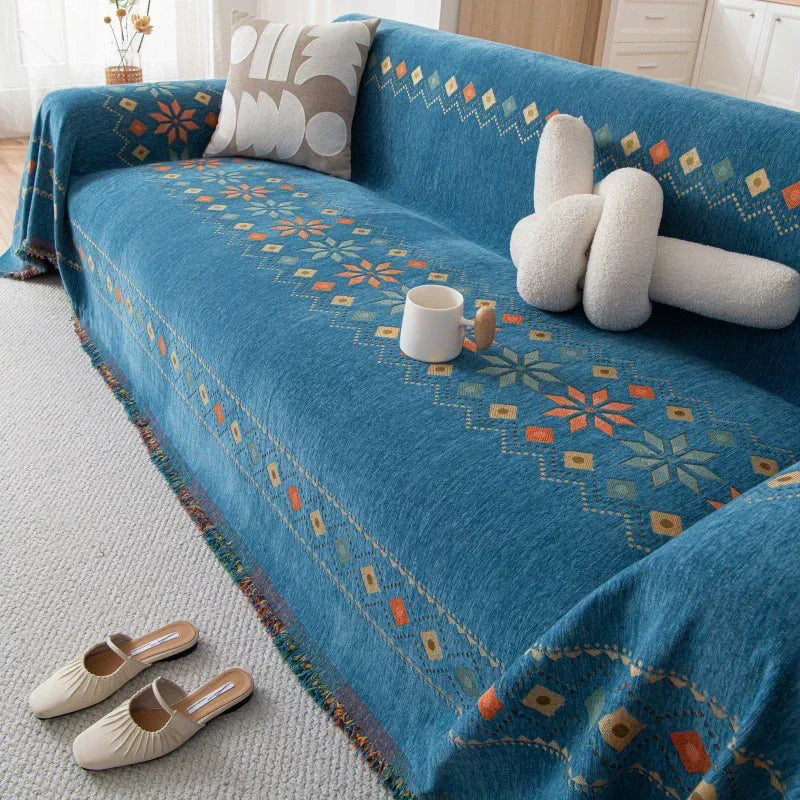 A deep blue bohemian accent sofa cover featuring geometric patterns and cream-colored decorative pillows.