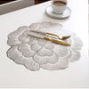 Gold plated peony coasters with a delicate floral pattern resting on a white table.