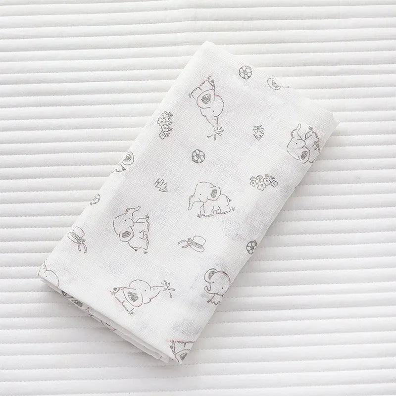 A white muslin swaddle blanket featuring a repeating pattern of cute animal designs on a striped background.