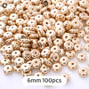 A pile of small, round, gold-colored geometric acrylic beads for jewelry making