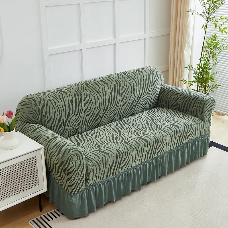 A moss green anti-slip jacquard sofa slipcover draped on a light-colored floor.