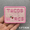 Pink embroidered patch with the text TACOS AND MYRGS on a gray background