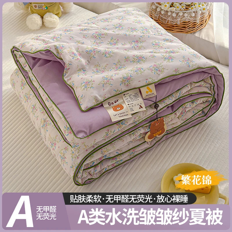 A lightweight summer quilt featuring a cartoon pattern, shown folded on a white surface.