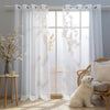 White sheer tulle window curtains hanging in a light-filled room with natural light streaming through.