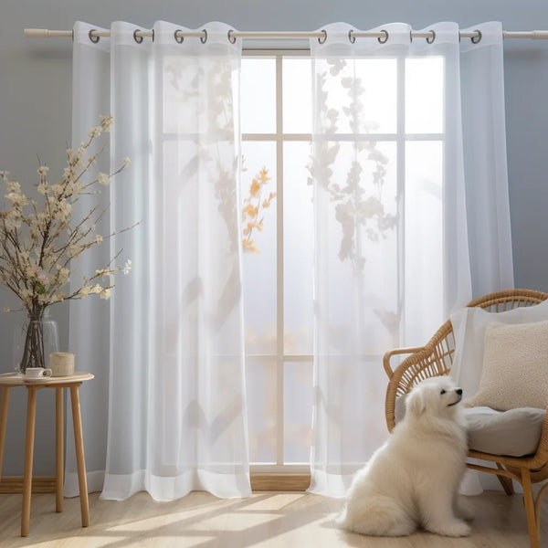White sheer tulle window curtains hanging in a light-filled room with natural light streaming through.
