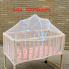 A wooden crib with a sheer mesh mosquito net covering the sides and top