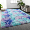 A vibrant tie-dye shaggy rug featuring shades of purple, blue, and teal on a gray floor.