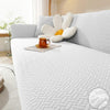 A white textured sofa cover featuring a large, light-colored floral accent cushion on a light gray sofa.