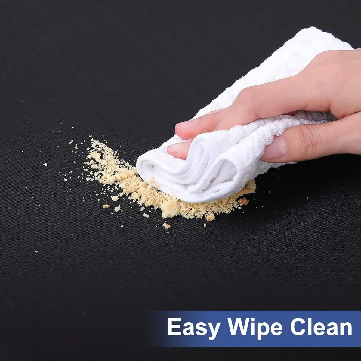 A hand wipes a yellow substance onto a black surface with a white cloth, demonstrating easy wipe clean.