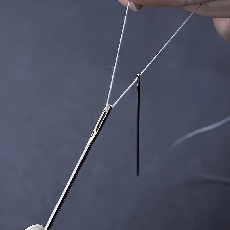 A hand is using a stainless steel hand sewing needle to thread white thread.