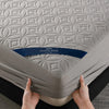 A gray quilted mattress protector labeled Healthy Sleep is being held by hands.