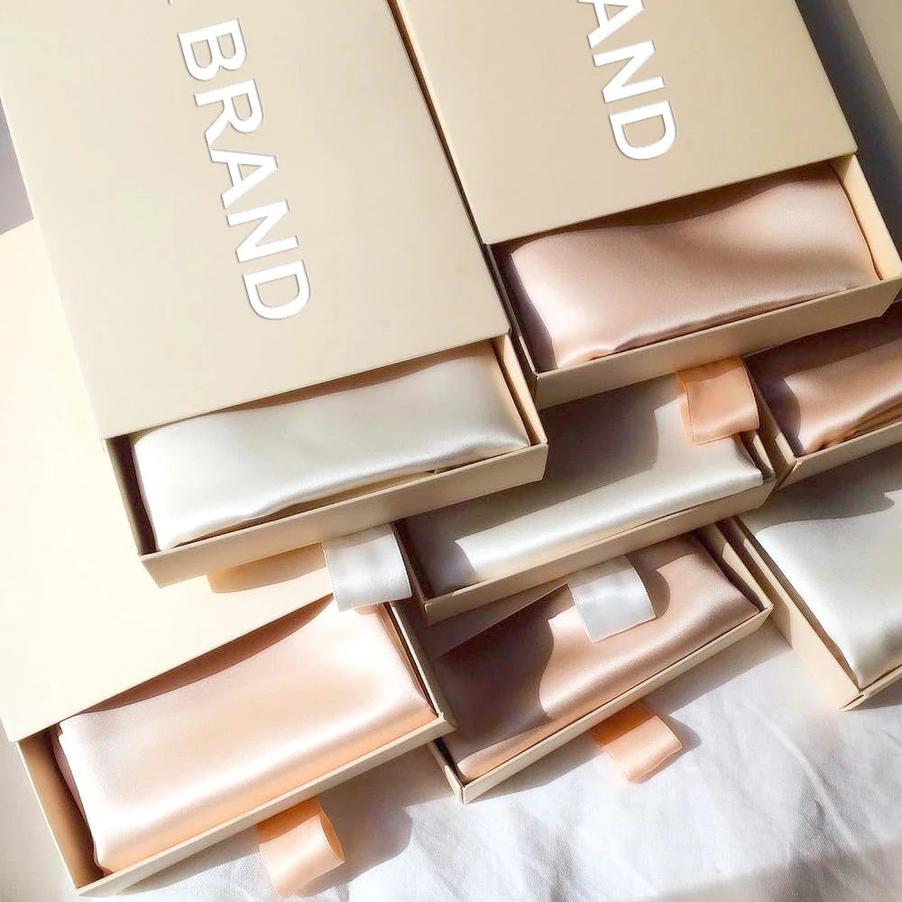 Several boxes of Mulberry silk pillowcases in nude and rose gold colors are displayed.