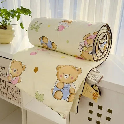 A rolled Summer Gauze Cotton Quilt with a bear design is displayed on a white surface.